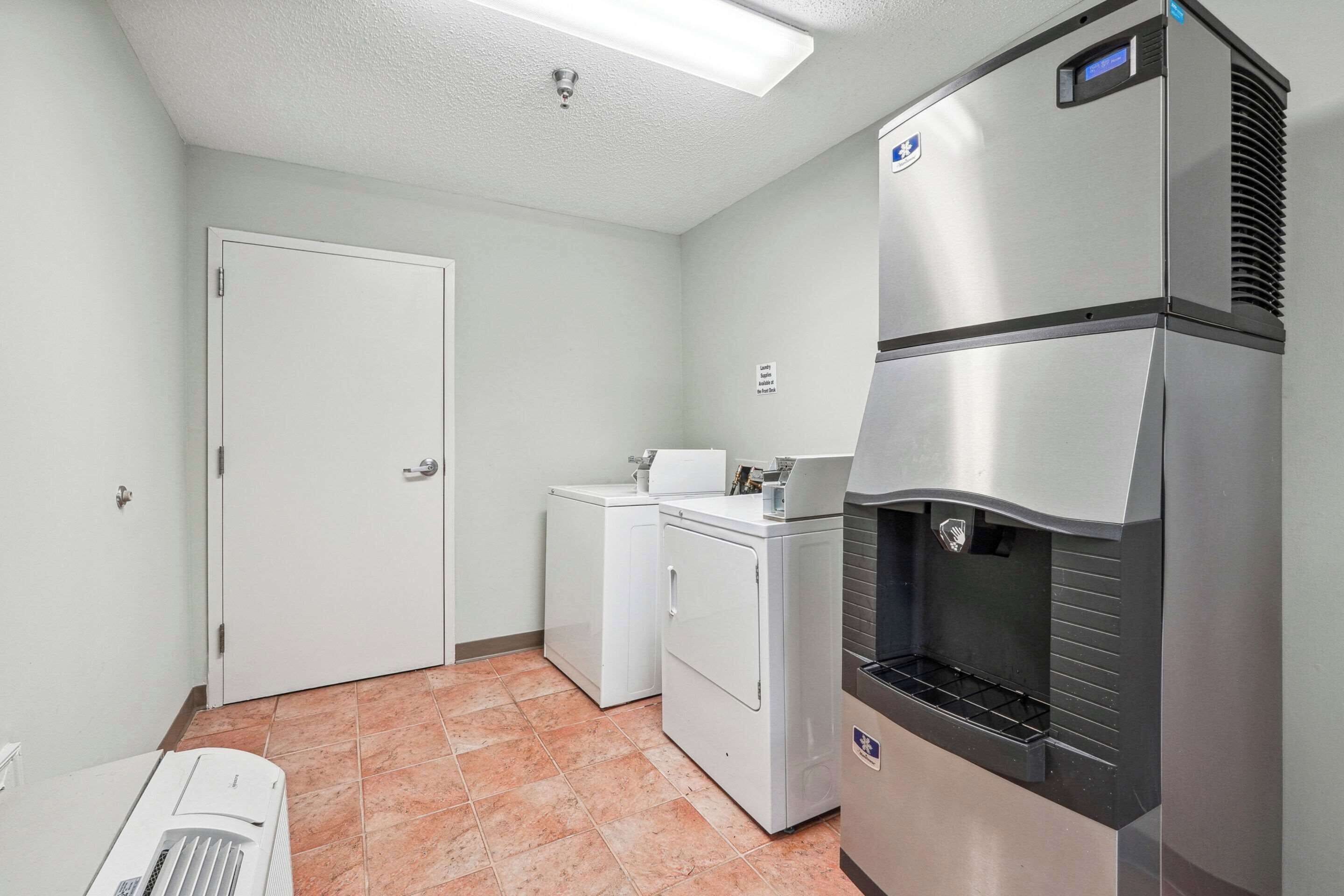 Una cocina compacta con refrigerador, lavadora y microondas.