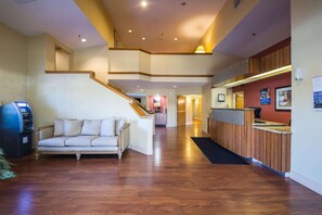 A hotel lobby with a wooden staircase, a reception desk, a sofa, and a vending machine. - Motel 6 Indianapolis, IN - Airport (Indianapolis)