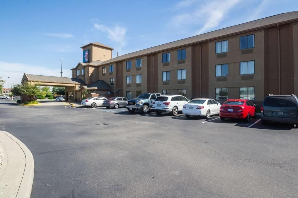 A hotel with a parking lot containing various cars.