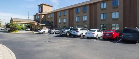 A hotel with a parking lot containing various cars.