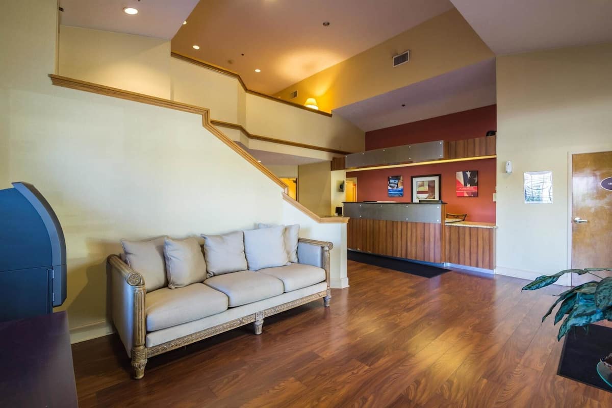 A spacious living area with a wooden staircase, a reception desk, and a sofa.