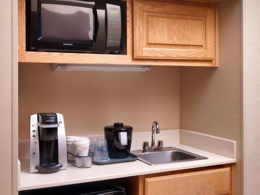 A compact kitchenette with a microwave, coffee maker, and sink.