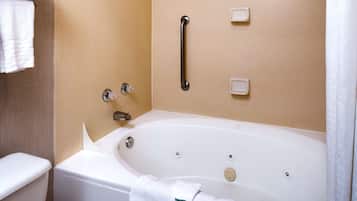 A modern bathroom with a bathtub, a shower, and a toilet. There are towels on the wall and a handrail above the bathtub.