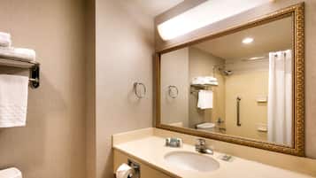 Une salle de bain d’hôtel avec un grand miroir, un lavabo, des toilettes et un porte-serviettes.
