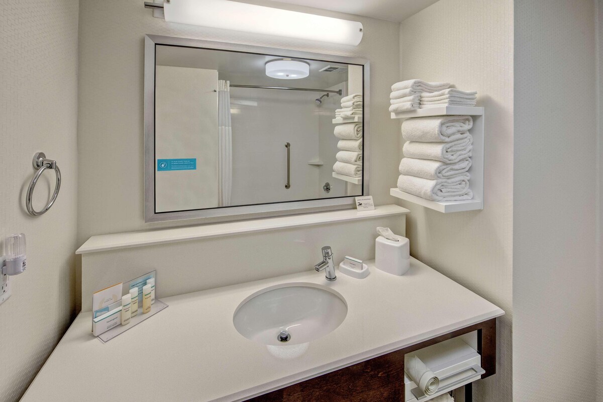 Un baño moderno con un espejo grande, un lavamanos y un perchero para toallas.