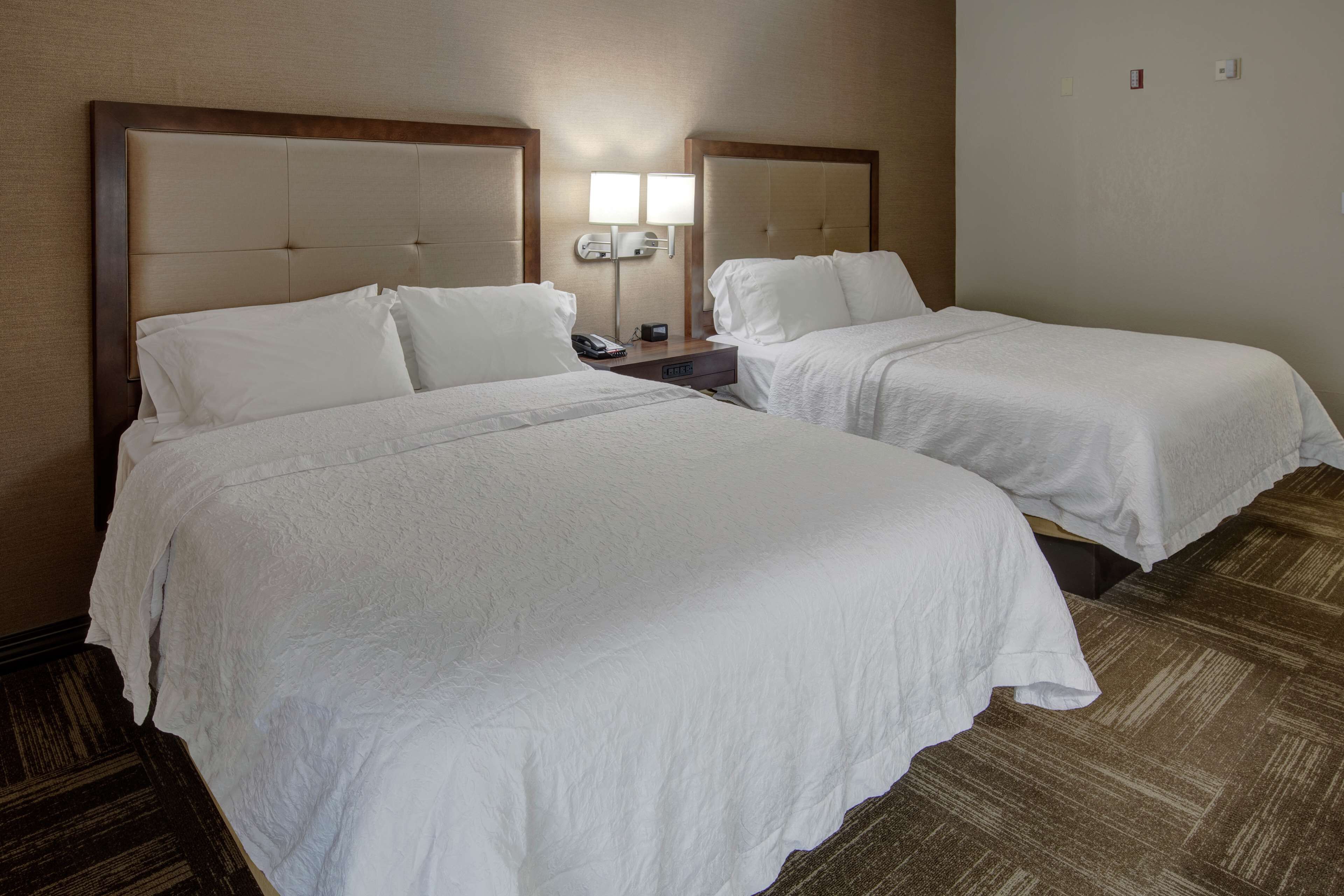 Habitación de hotel con dos camas, una mesita de noche con lámpara y un teléfono.