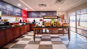 A breakfast area with a checkered floor, a table with food items, and a wall with breakfast-related decorations. - Hampton Inn Oklahoma City/Edmond (Edmond)