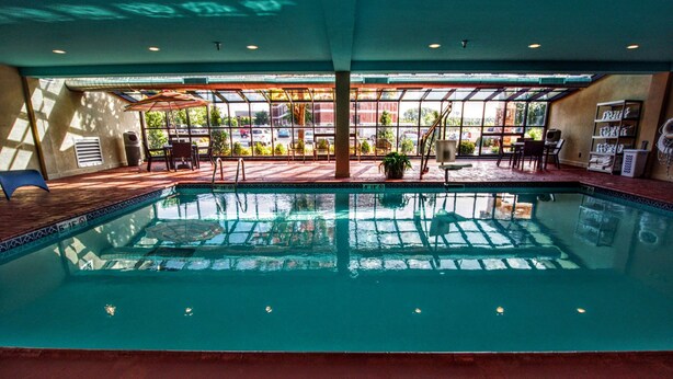 An indoor swimming pool with clear water, surrounded by sunlit patio seating and a view of the outside. - Hampton Inn Oklahoma City/Edmond (Edmond)