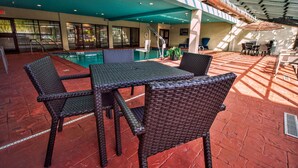 An outdoor patio with wicker furniture, a pool, and a covered area with a view of the street. - Hampton Inn Oklahoma City/Edmond (Edmond)