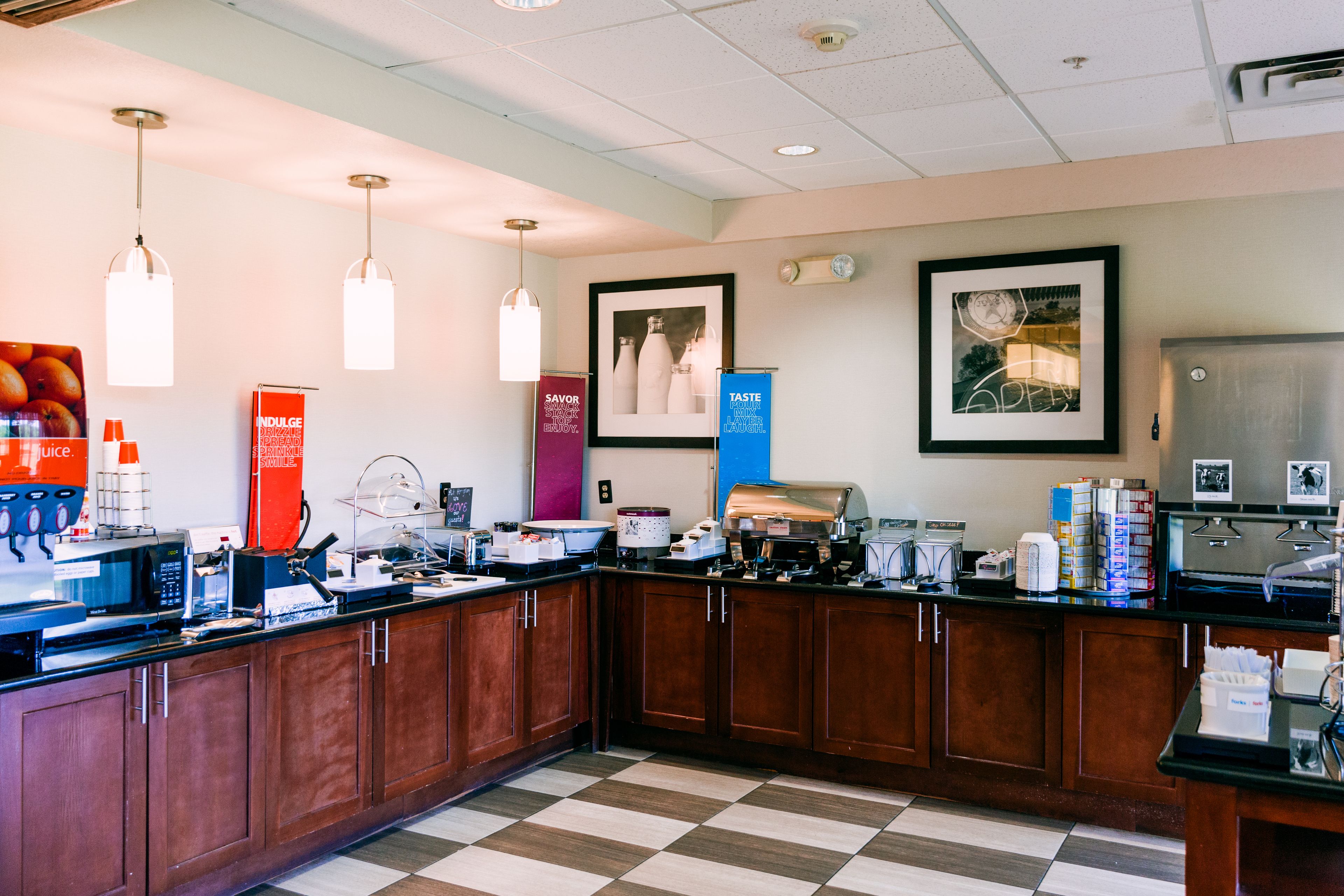 A hotel kitchen with wooden cabinets, a checkered floor, and various kitchen appliances.
