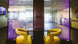 A modern interior with a glass partition, two yellow chairs, and a table. - Hampton Inn Oklahoma City/Edmond (Edmond)