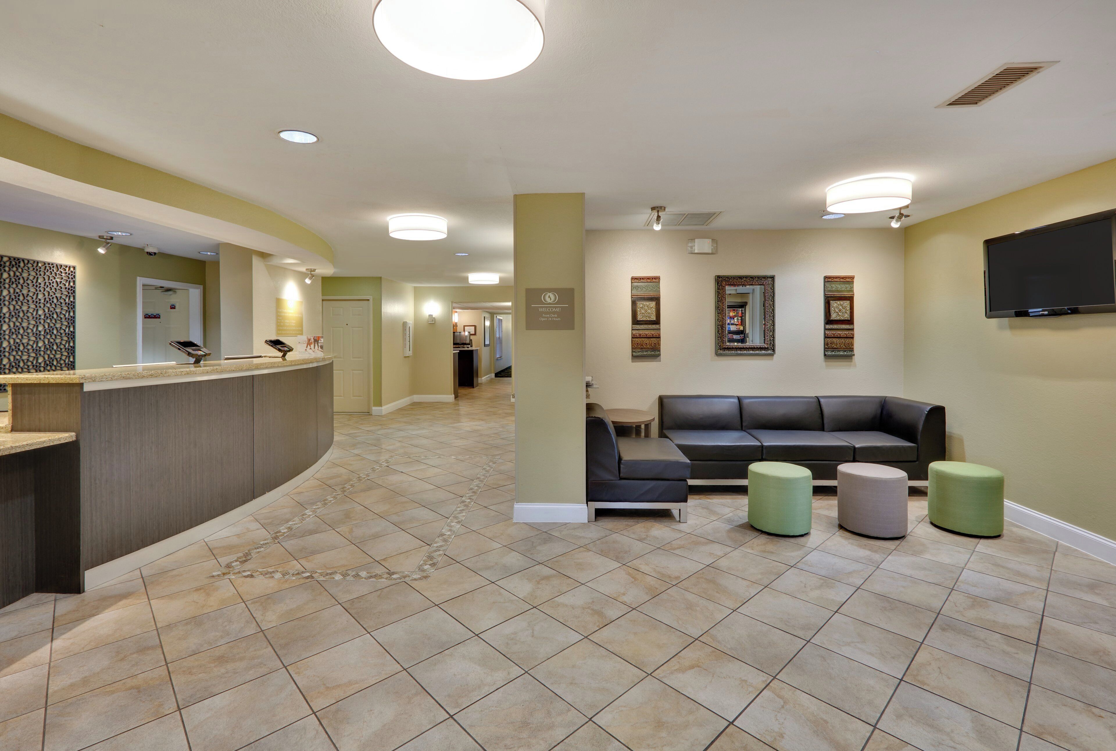 A reception area with a curved counter, a reception desk, a black leather sofa, and three ottomans.