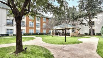 A courtyard with a tree, a patio area, and a building with multiple windows.