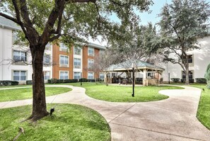 A courtyard with a tree, a patio area, and a building with multiple windows. - Candlewood Suites Market Center by IHG (Dallas)