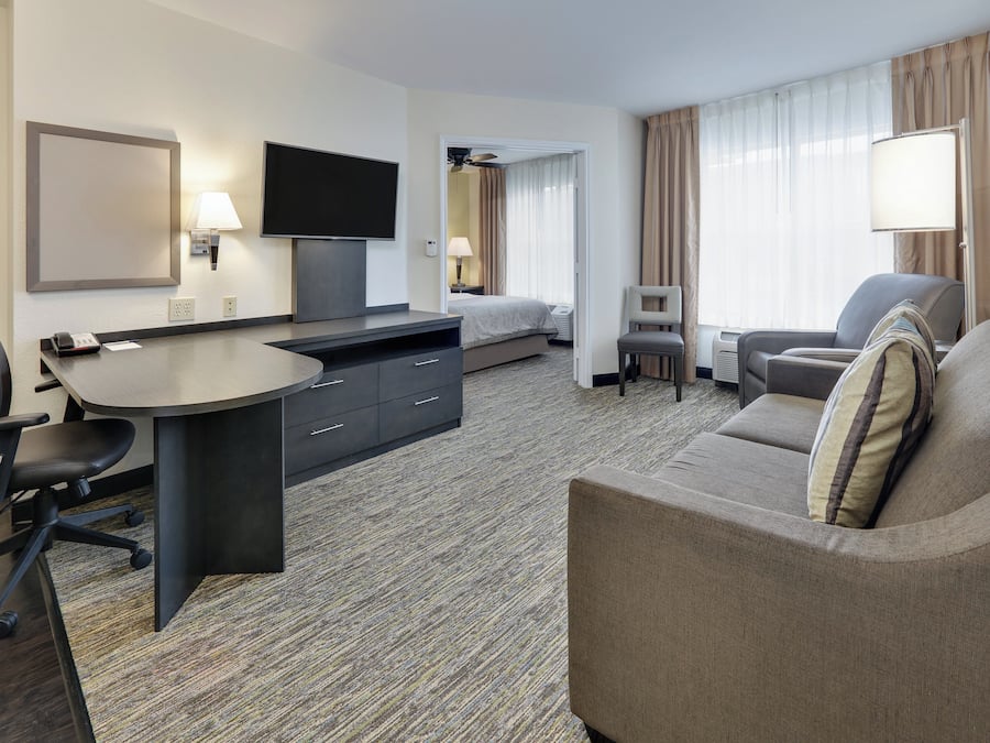 Een hotelkamer met een bureau, stoel, bed en een slaapbank.