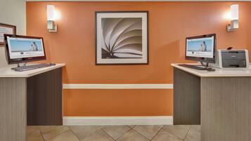 A reception area with two computer stations, a framed artwork on the wall, and a Brother printer.