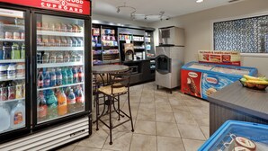 A convenience store with a refrigerated beverage cooler, a coffee machine, and a counter with snacks and drinks. - Candlewood Suites Market Center by IHG (Dallas)