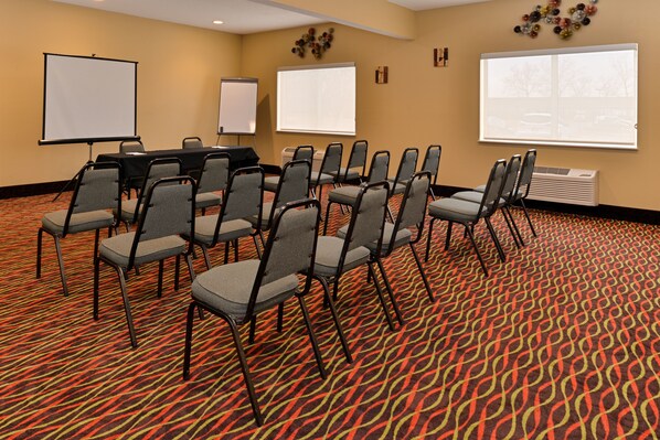 A conference room with a patterned carpet, multiple chairs, a table, and two projection screens.