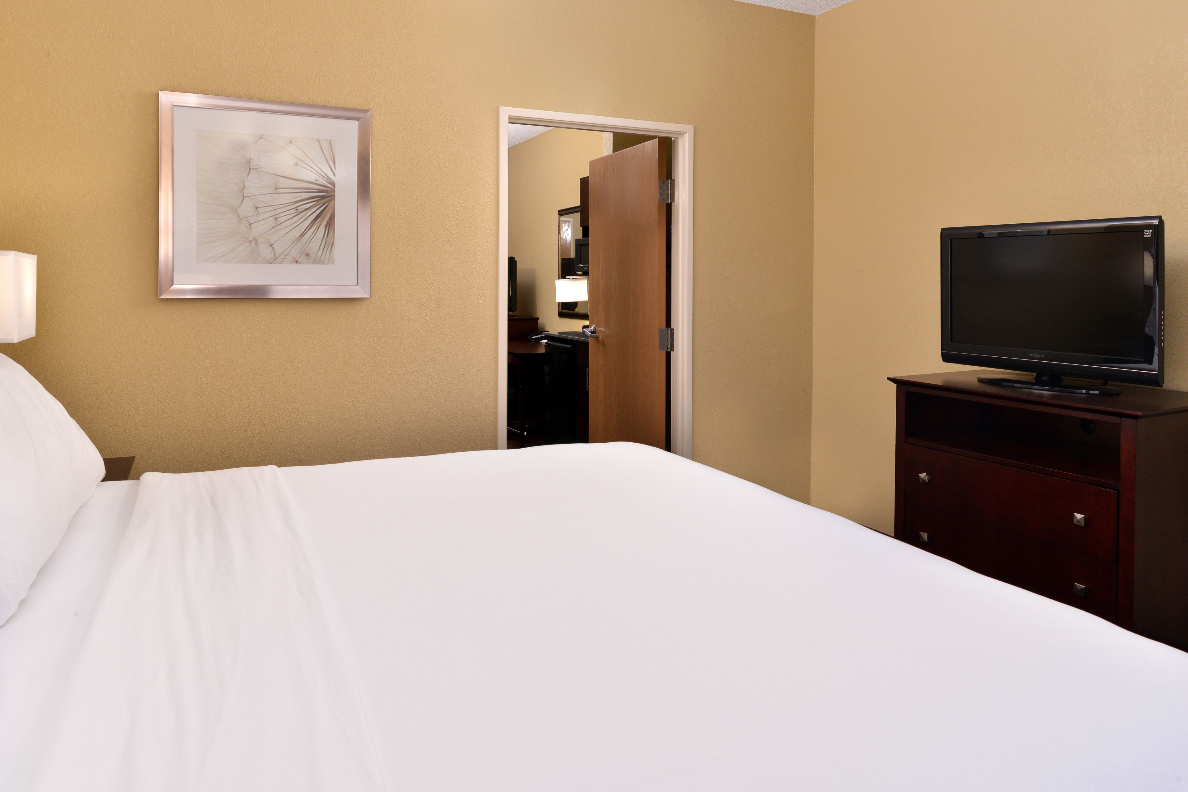 Ein Hotelzimmer mit einem Bett, einem Fernseher auf einem Holztisch und einem gerahmten Bild an der Wand.