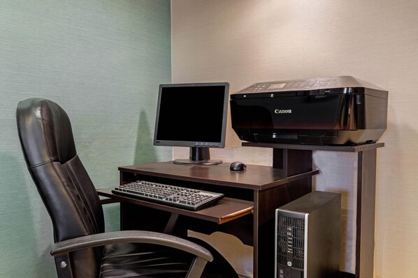 A modern office setup with a desk, chair, computer monitor, keyboard, and printer.