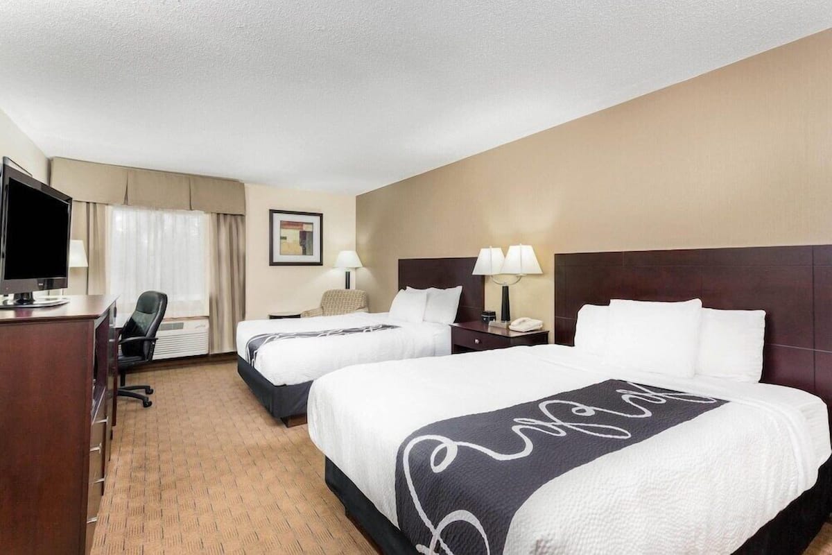 Une chambre d’hôtel avec deux lits, un bureau, une télévision et une chaise.
