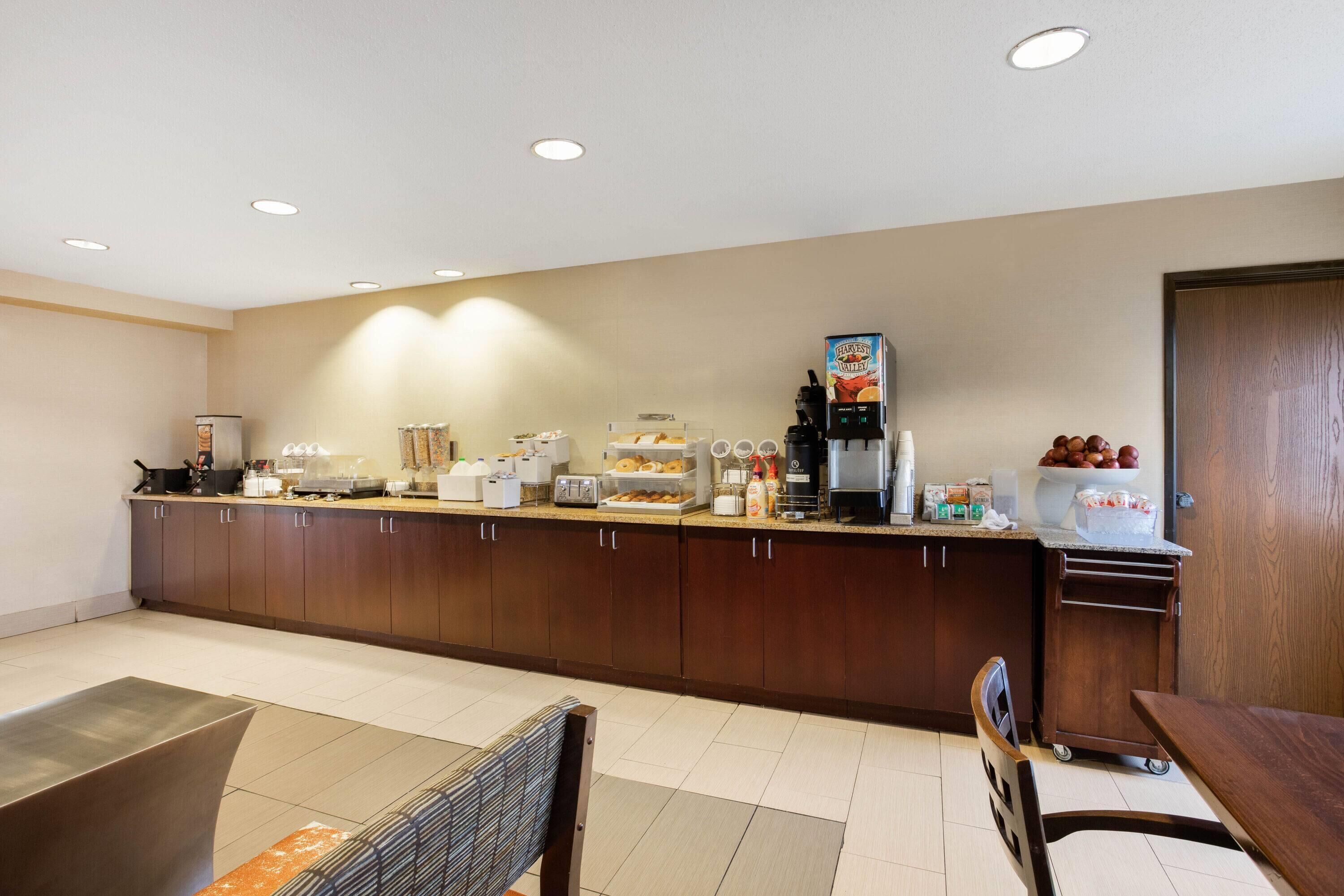 A modern kitchen with a long counter, equipped with various appliances and a coffee machine.