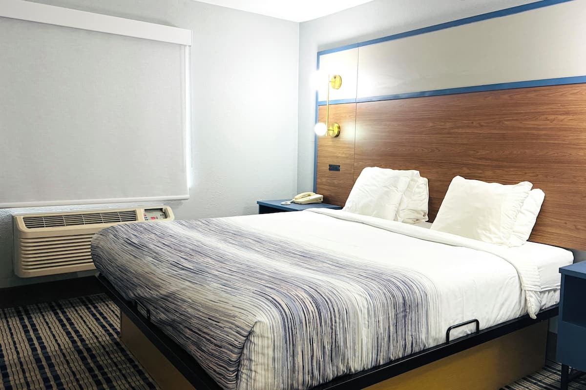 Une chambre d’hôtel équipée d’un lit, d’une table de chevet, d’une lampe et d’un radiateur fixé au mur.