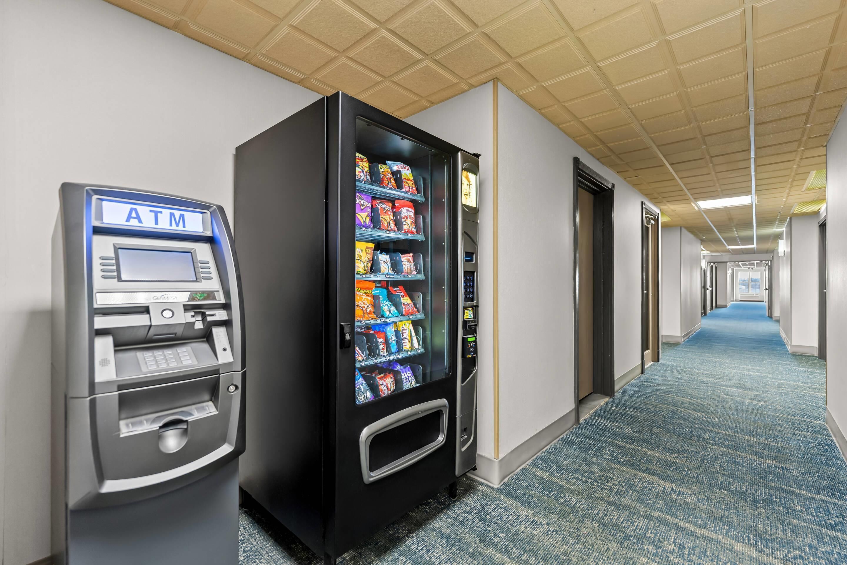 Een binnengang met een pinautomaat en een automaat voor snacks.