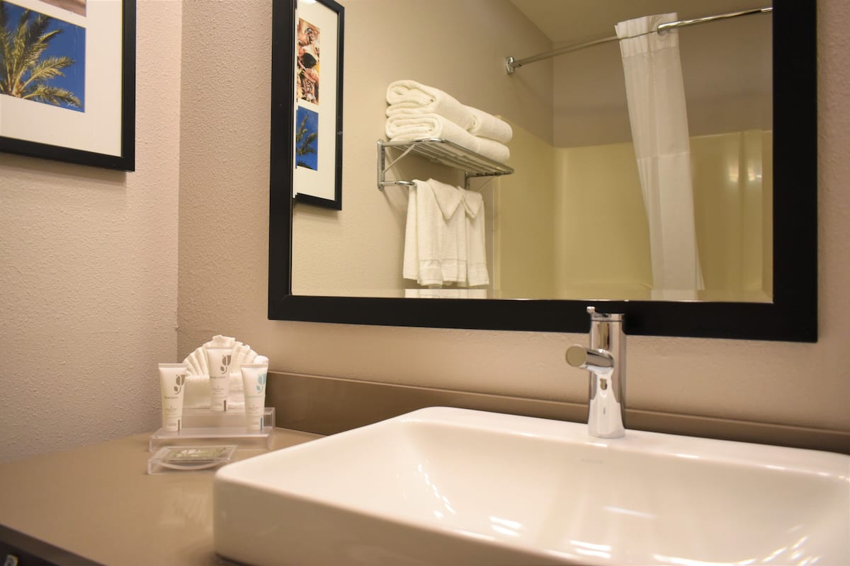 A bathroom with a sink, mirror, towel rack, and framed pictures on the wall.