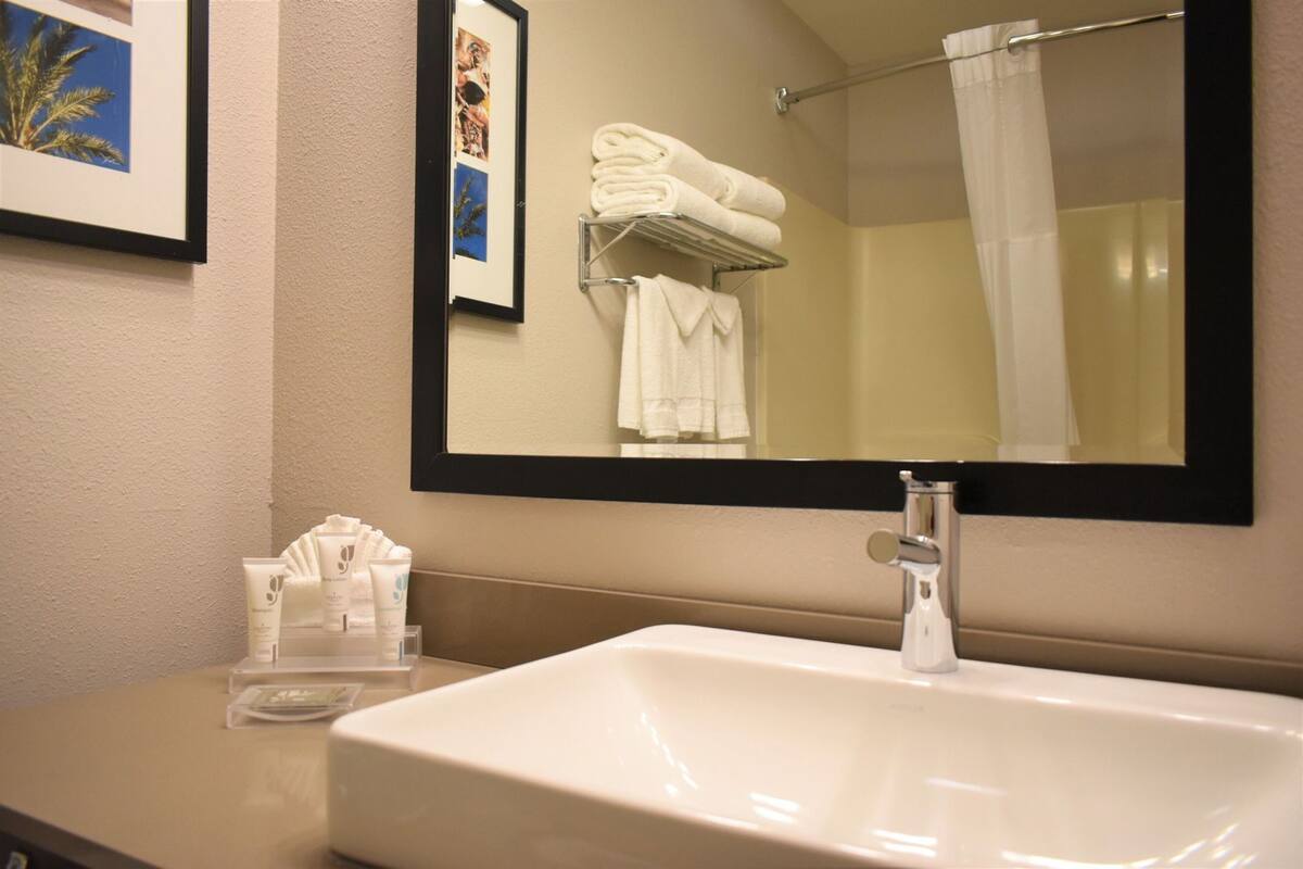 A bathroom with a sink, mirror, towel rack, and framed pictures on the wall.