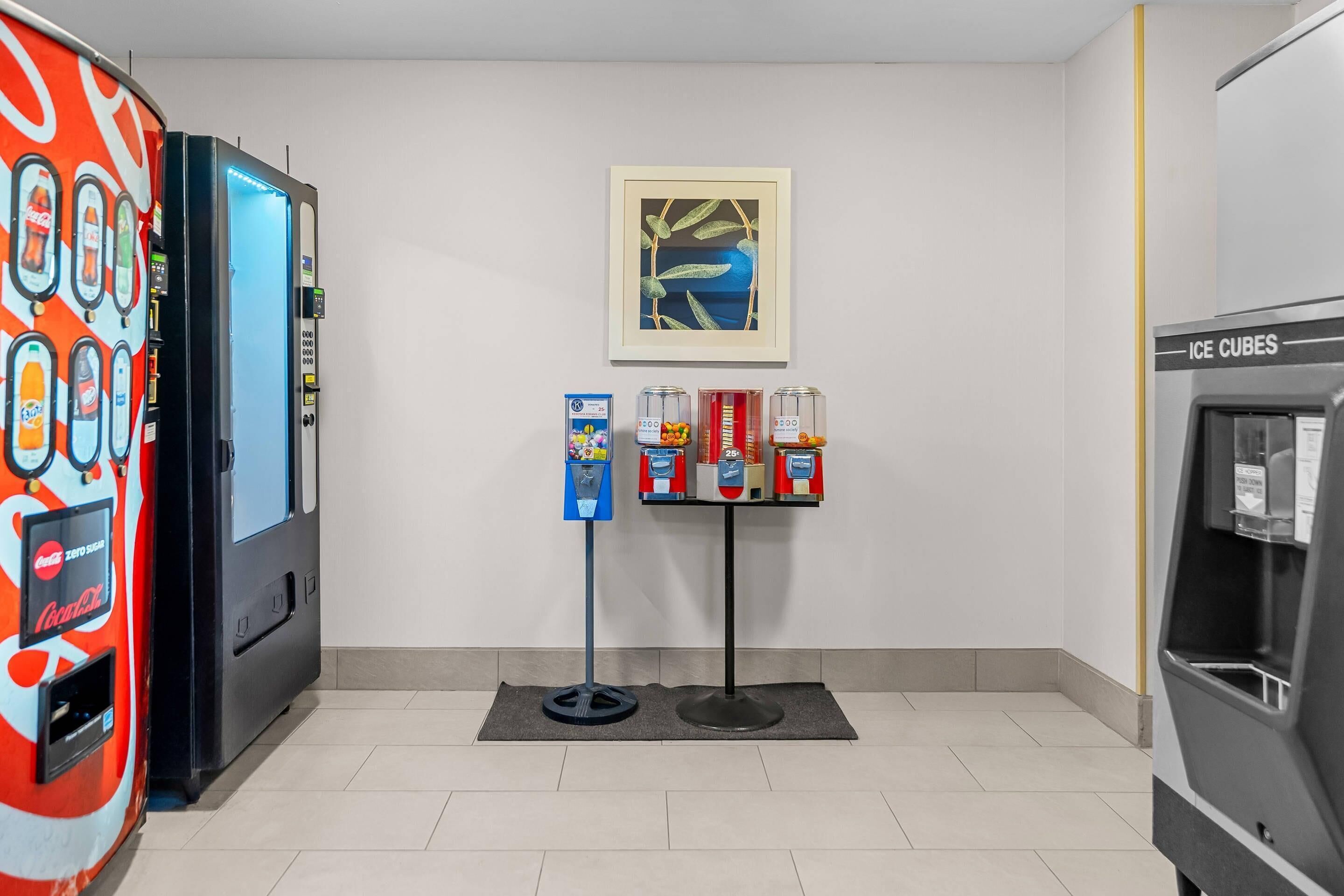 A vending machine area with a Coca-Cola machine, a Coca-Cola Zero machine, and an ice cube dispenser.