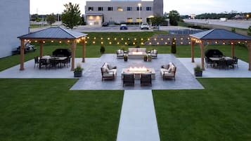 An outdoor patio area with seating and a fire pit, surrounded by string lights.