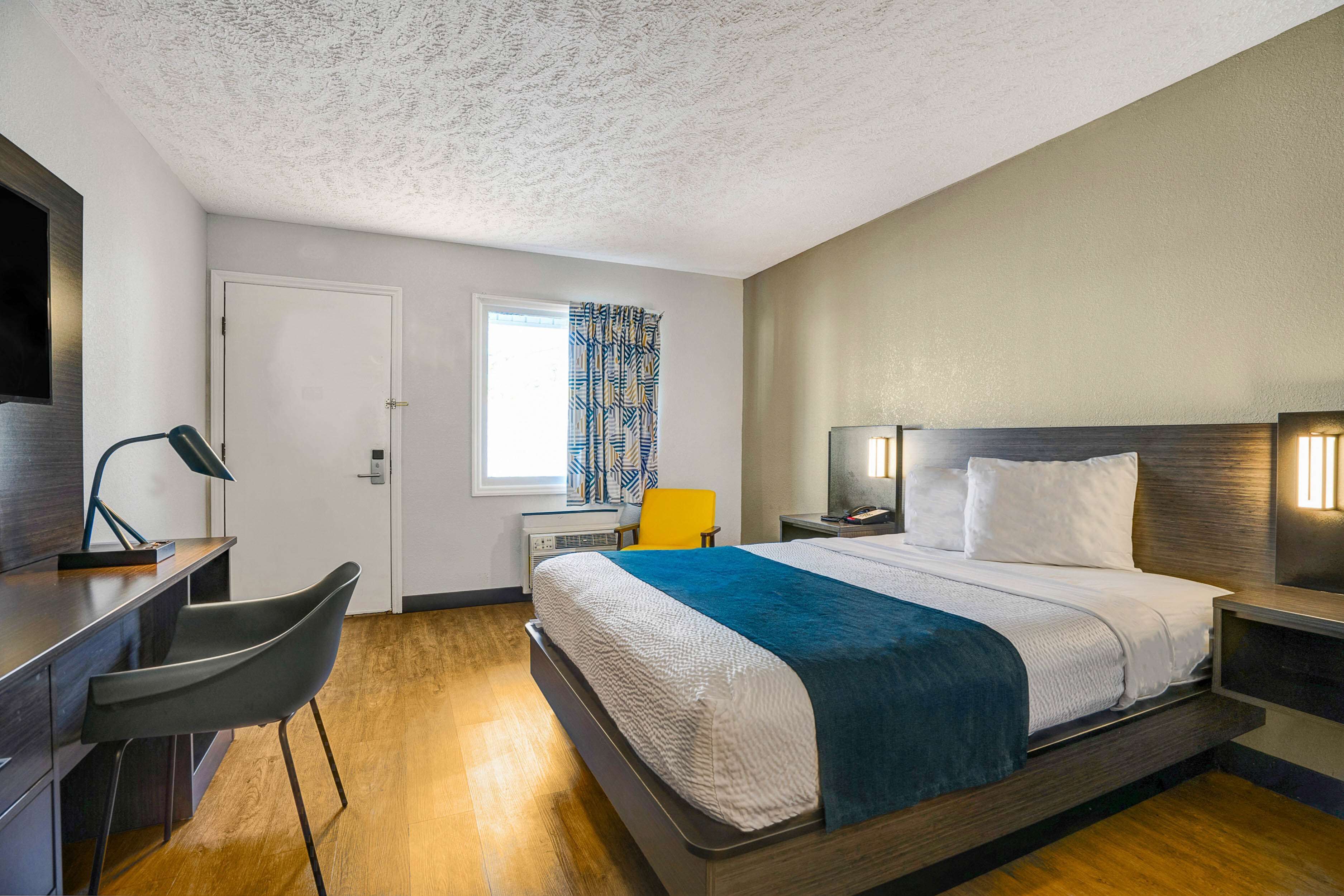 Una habitación de hotel moderna con cama, escritorio y silla.