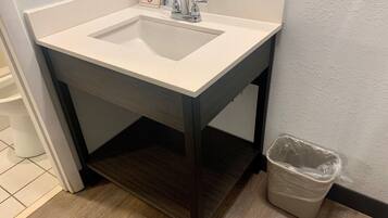 A bathroom sink with a mirror, a trash bin, and a towel rack.
