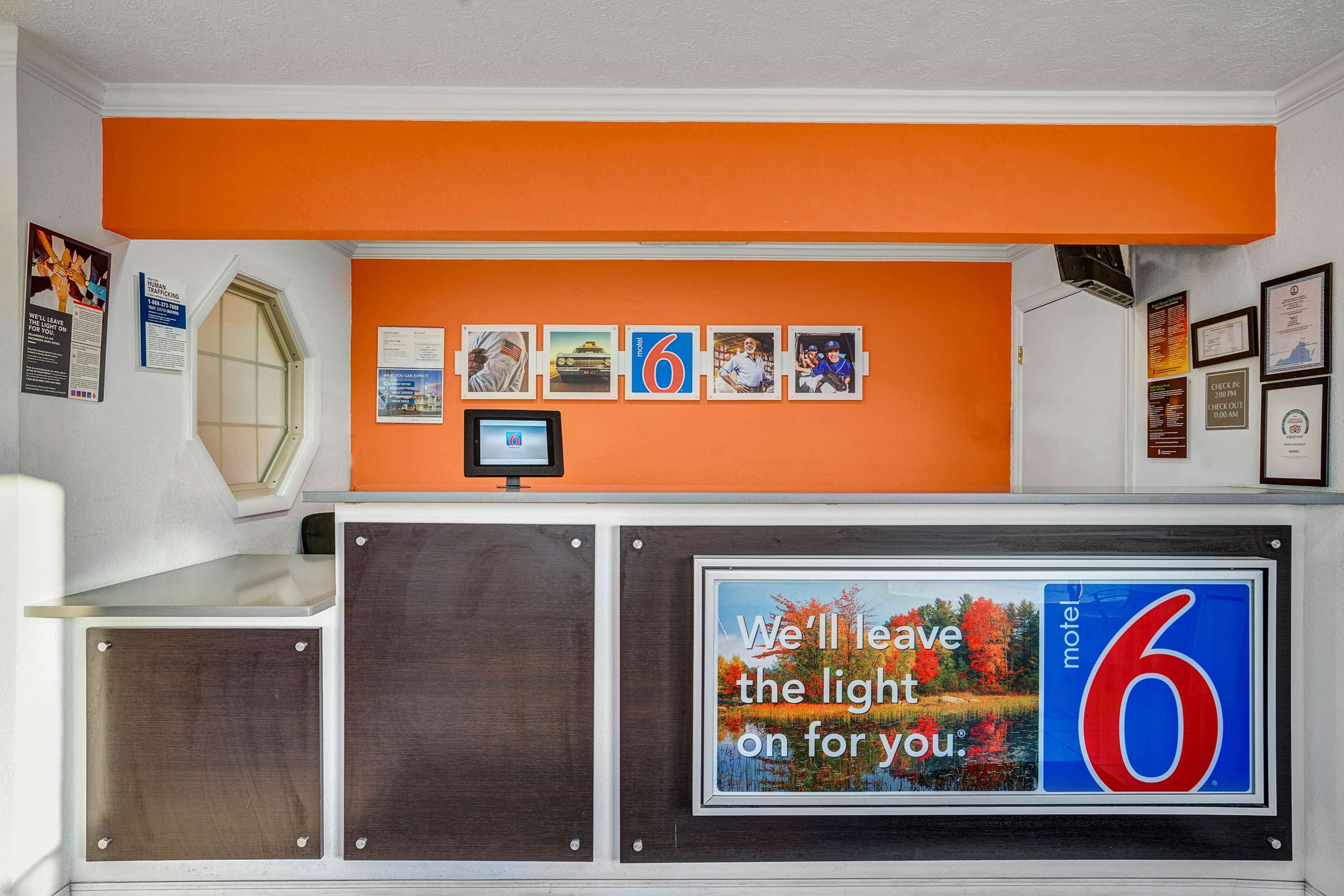 L’intérieur d’un motel, avec un mur décoré de tableaux encadrés et une grande enseigne indiquant : « Nous laisserons la lumière allumée pour vous. »
