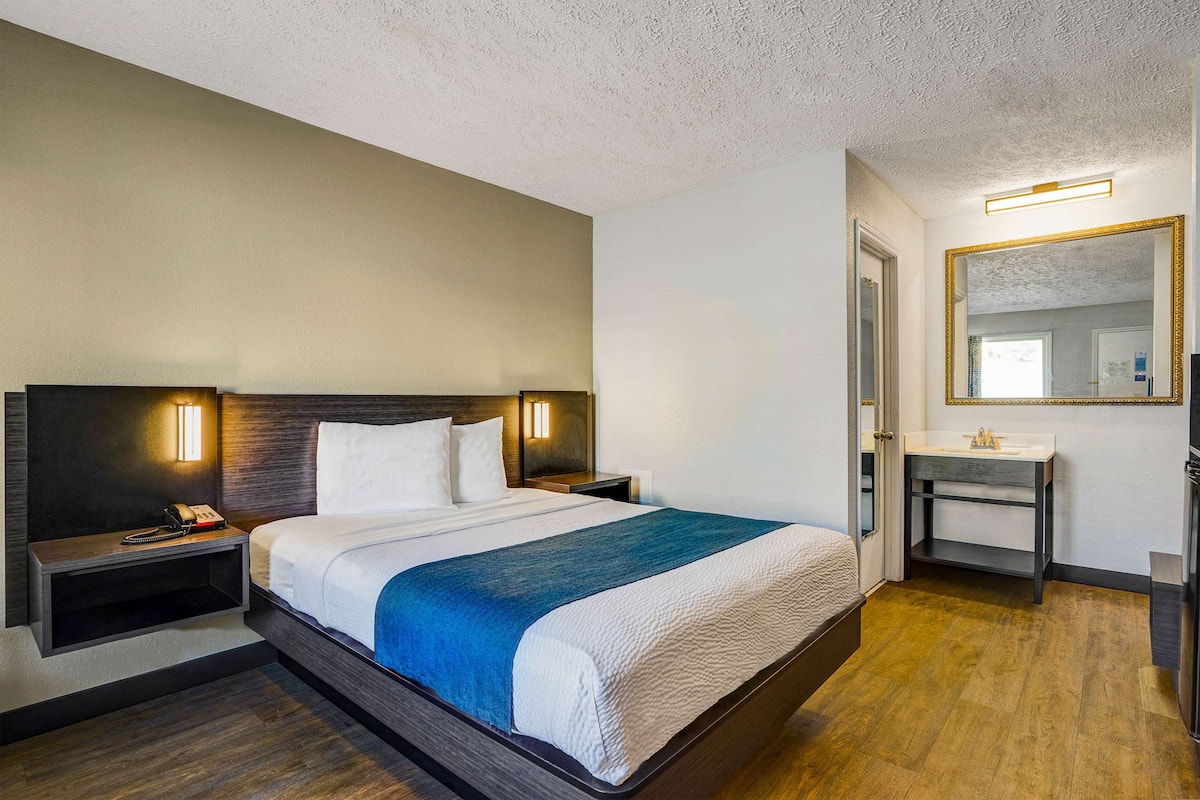Ein Hotelzimmer mit Bett, Nachttischen, Waschbecken und Tür.