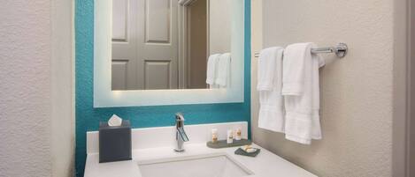 A bathroom with a white sink, a mirror, and a towel rack.