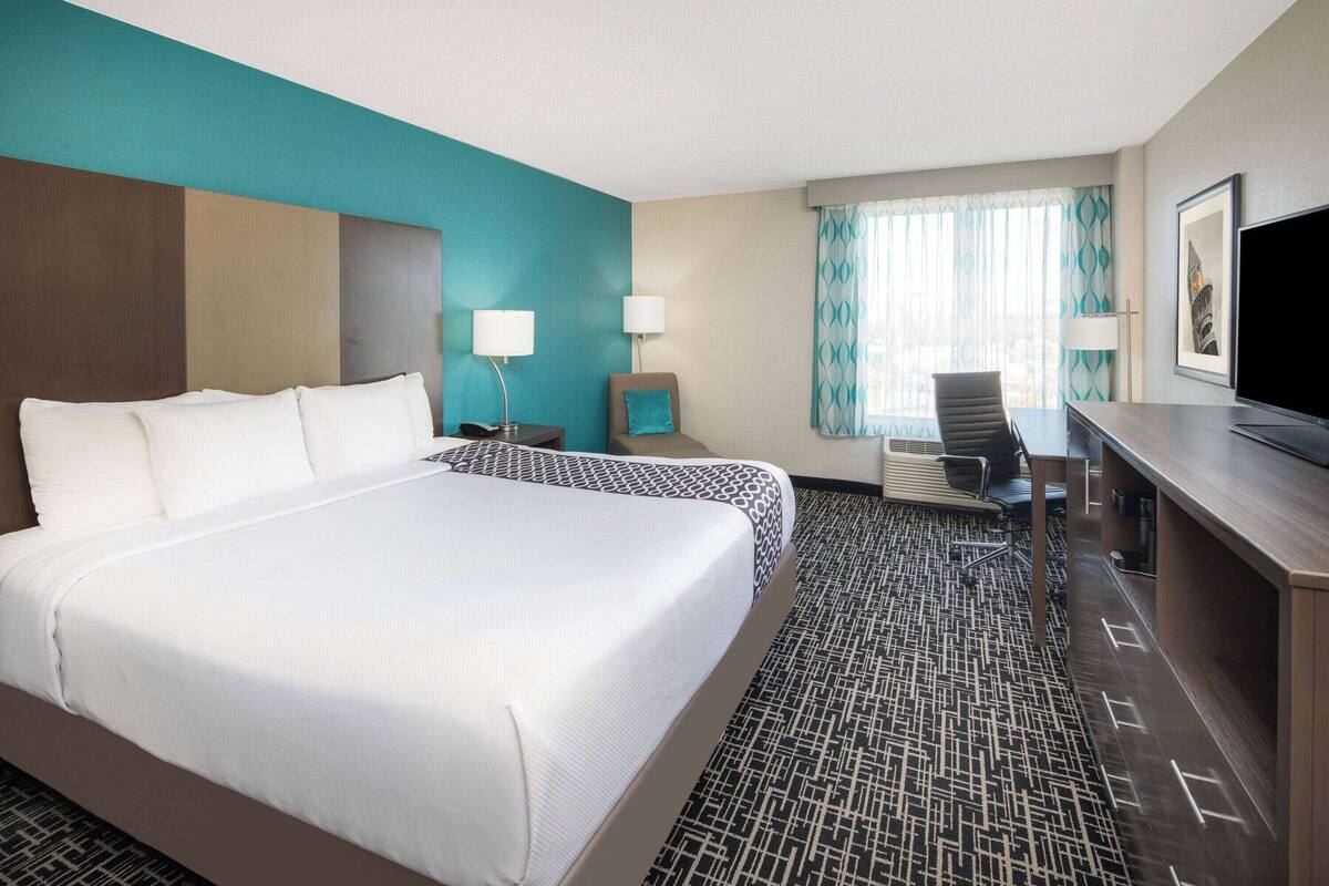 Une chambre d’hôtel avec un grand lit, un bureau, une chaise et un téléviseur.