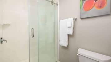 A bathroom with a glass shower enclosure, a toilet, and a wall-mounted towel rack with two white towels.