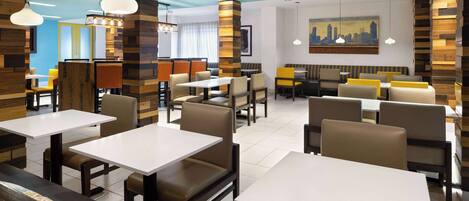 A modern restaurant interior with multiple dining tables and booths, wooden accents on the walls, and a cityscape painting on the wall.