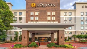 Een La Quinta hotel met een moderne gevel, een overdekte ingang en een aangelegde voortuin.