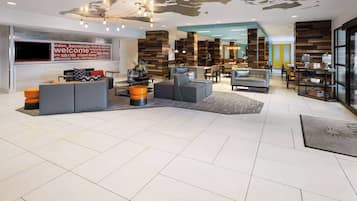 A spacious lobby with a large welcome sign, modern furniture, and a mix of seating areas.