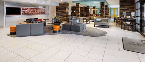 A spacious lobby with a large welcome sign, modern furniture, and a mix of seating areas.