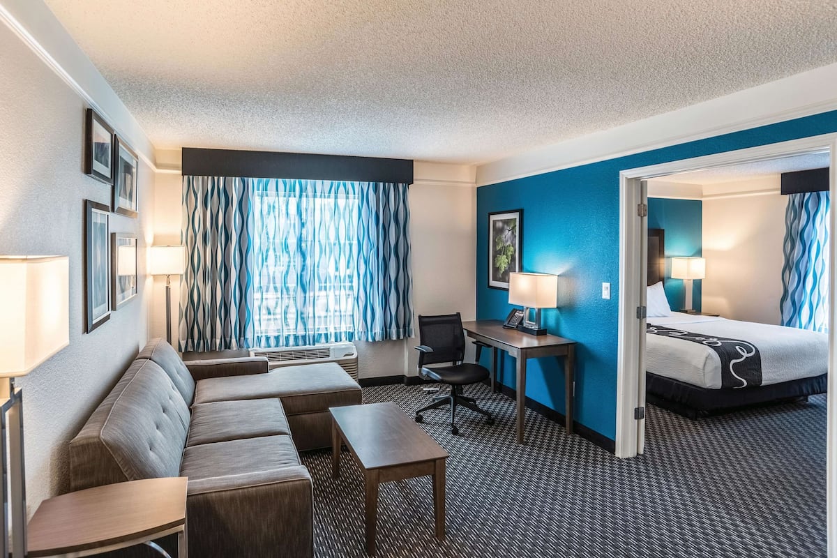 A hotel room with a sofa, desk, and bed.
