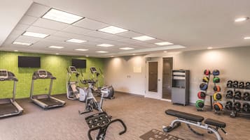 Une salle de sport équipée de tapis de course, de vélos d’appartement, d’un banc de développé couché et d’une série de poids.