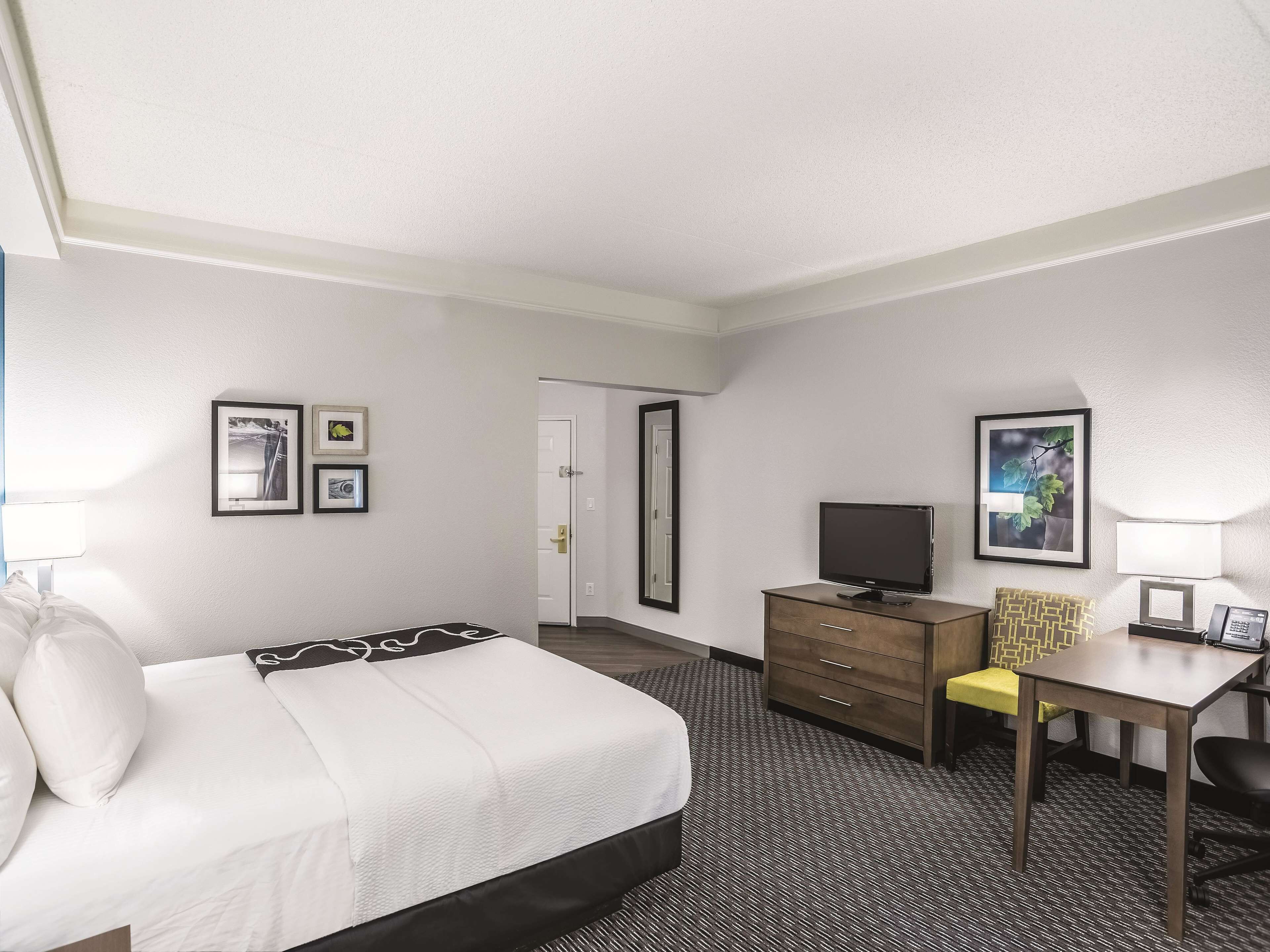 Ein Hotelzimmer mit einem Bett, einem Schreibtisch, einem Fernseher, einem Sessel und einer Kommode.