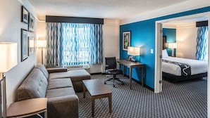 A hotel room with a sofa, desk, and bed. - La Quinta Inn & Suites by Wyndham Phoenix Chandler (Phoenix)