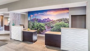 A reception area with a large wall mural of a desert landscape, a reception desk, and a modern design with a textured wall and a patterned floor. - La Quinta Inn & Suites by Wyndham Phoenix Chandler (Phoenix)