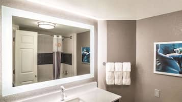 Un baño con un espejo grande, un lavabo, una ducha y un perchero para toallas.