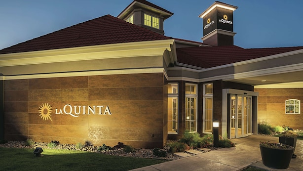 A hotel exterior with a prominent "La Quinta" sign, a well-lit entrance, and a landscaped garden area. - La Quinta Inn & Suites by Wyndham Phoenix Chandler (Phoenix)